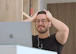 a man with glasses is looking at a laptop