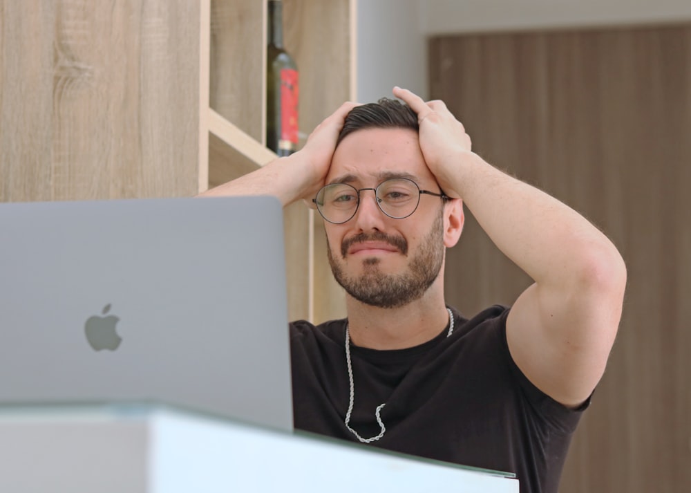Un hombre con gafas está mirando una computadora portátil