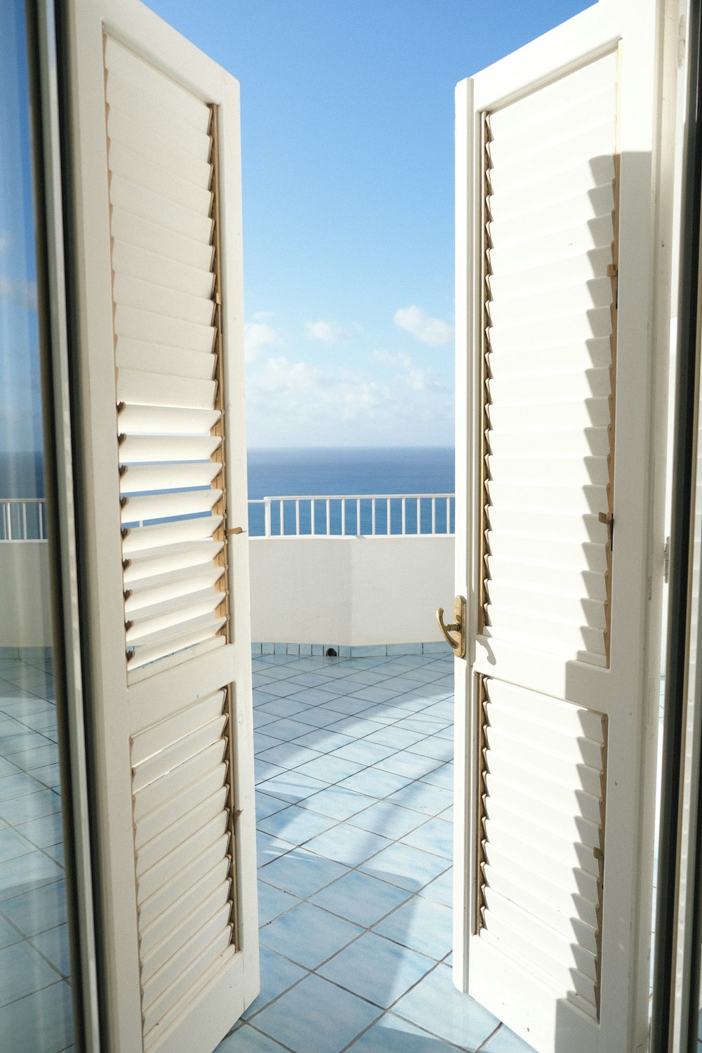 an open door leading to a balcony with a view of the ocean