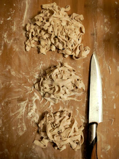 Close-up of freshly made bakmi Jawa noodles being hand-cut on a wooden board