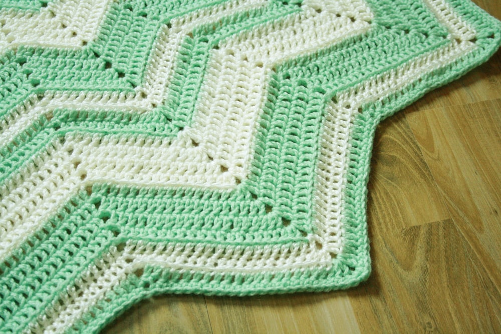 a crocheted blanket is laying on a wooden floor