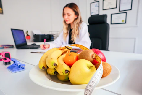 a woman sitting at a desk with a bowl of fruit