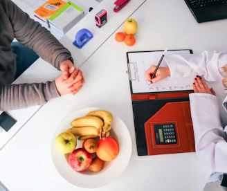 a couple of people sitting at a table with a plate of fruit