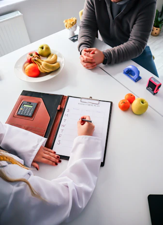 two people sitting at a table writing on a clipboard