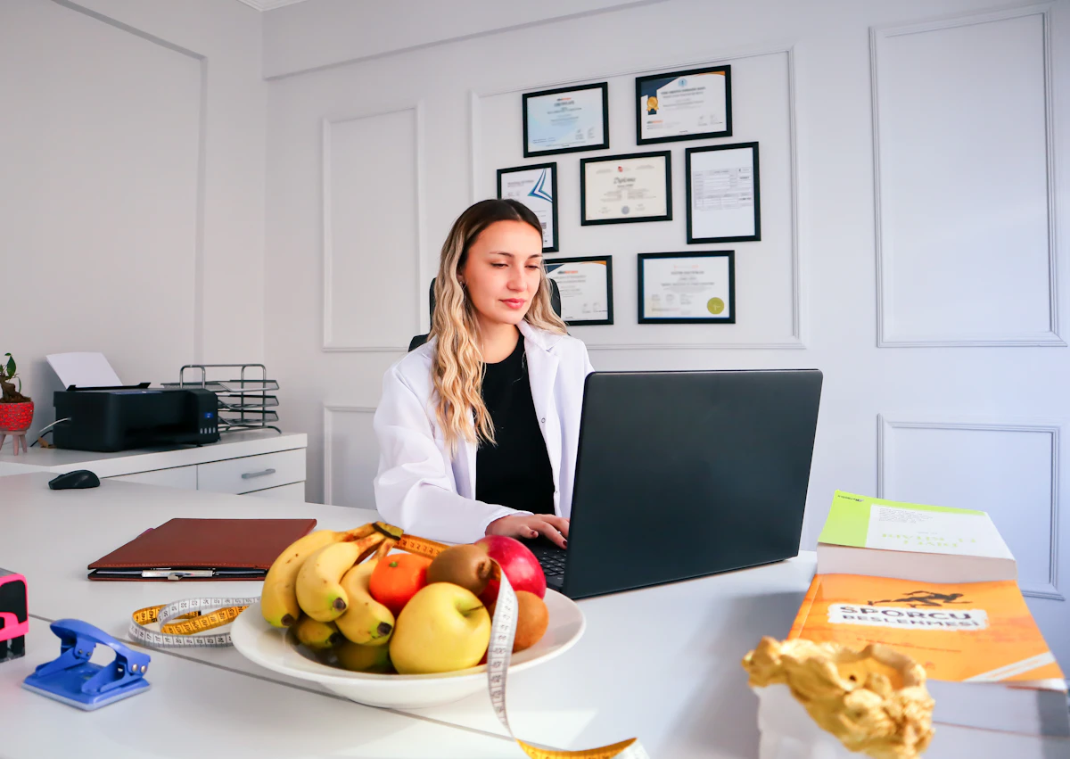 Dietitian working at a desk with a laptop, managing clinic appointments and meal plans