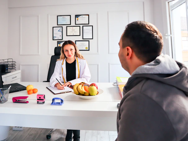 A friendly hospital receptionist assisting a patient with appointment details on a computer.