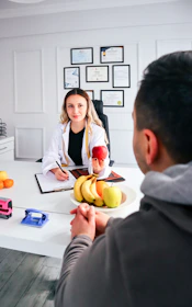 a man and woman sitting at a table with a plate of fruit