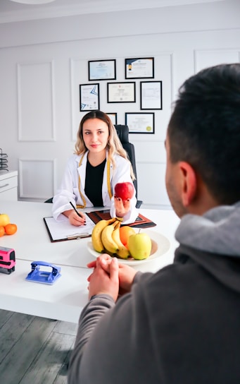 a man and woman sitting at a table with a plate of fruit