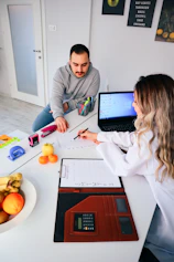 a man and a woman sitting at a table with a laptop