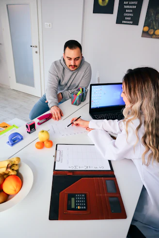 a man and a woman sitting at a table with a laptop