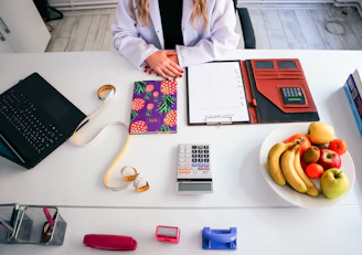 a woman sitting at a table with a plate of fruit and a calculator