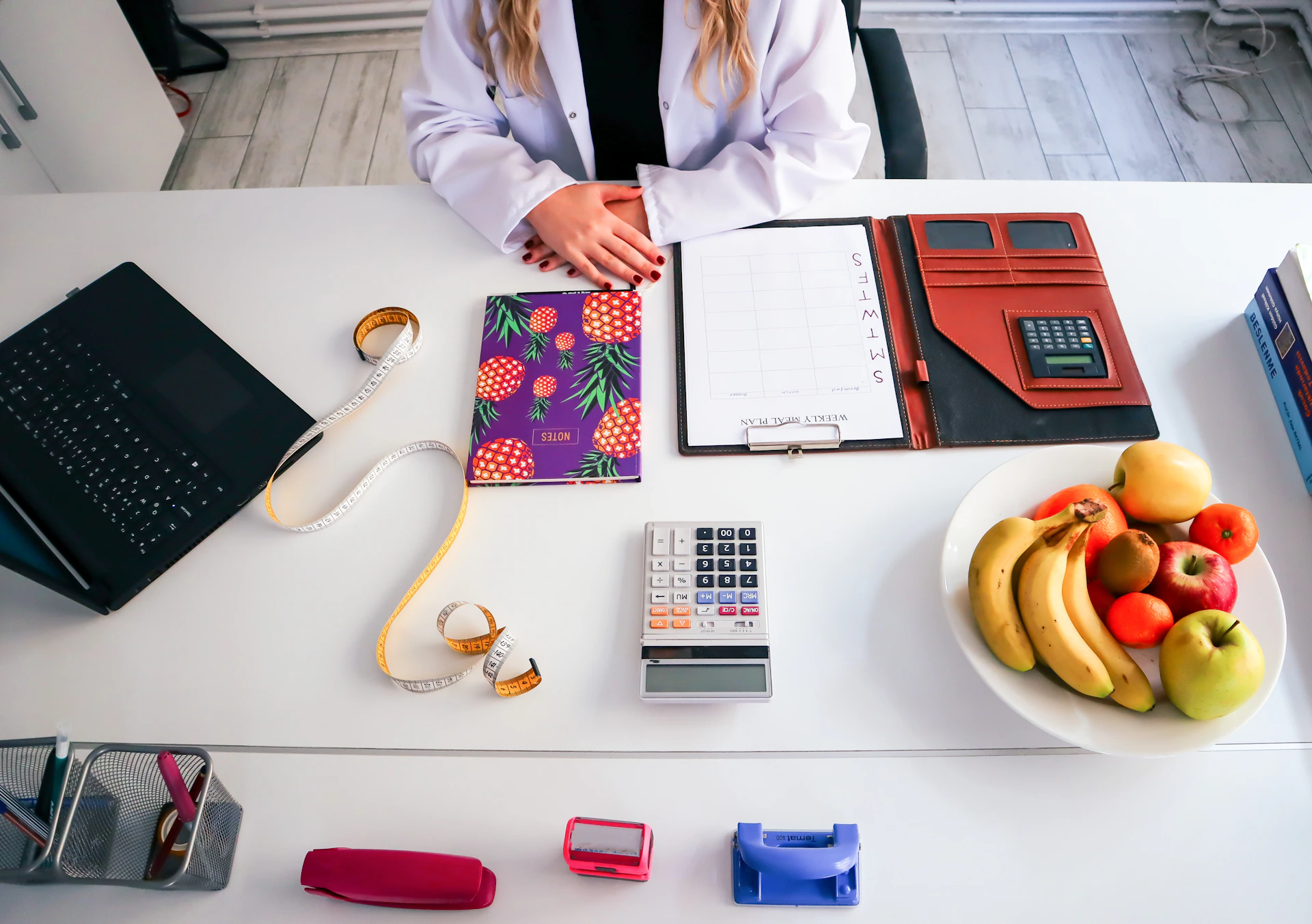 a woman sitting at a table with a plate of fruit and a calculator