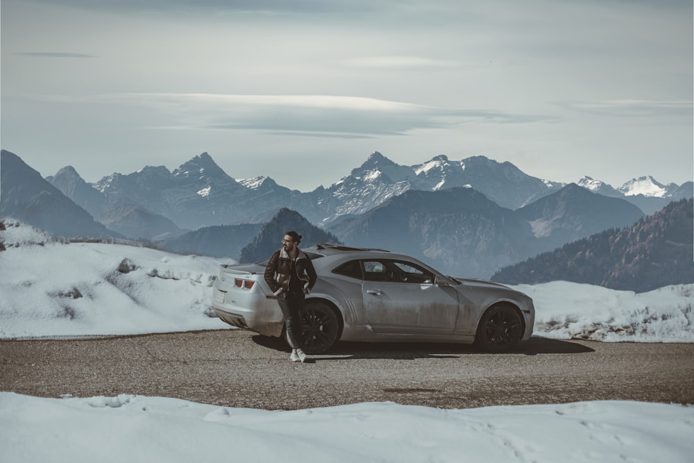 a man standing next to a car in the snow