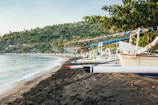 Traditional fishing boats anchored near a sandy Cat Ba beach.