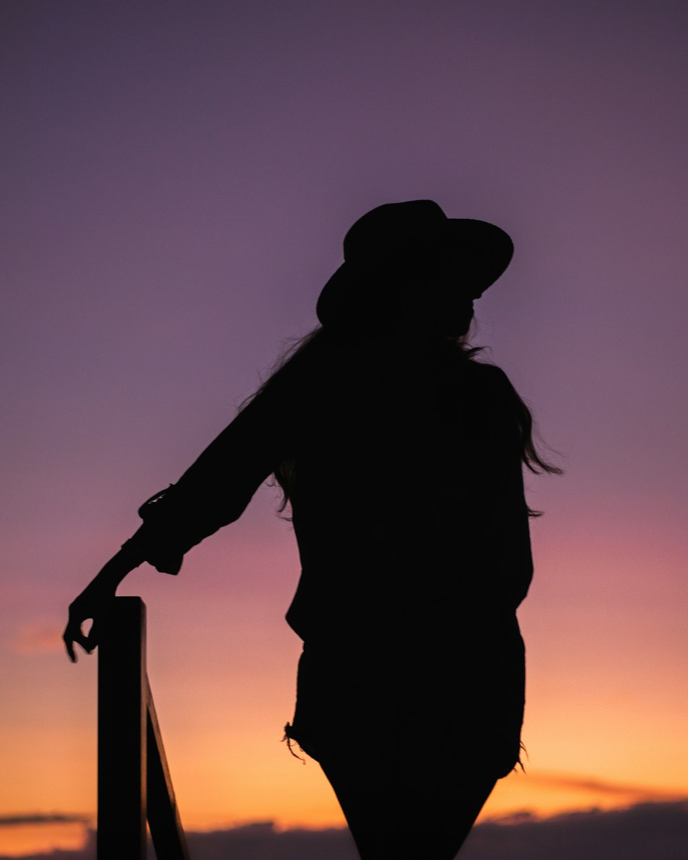 a silhouette of a person wearing a hat