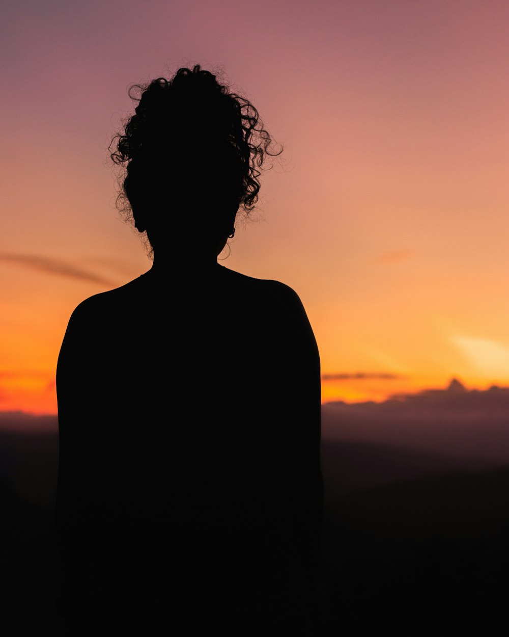 a silhouette of a person with a sunset in the background