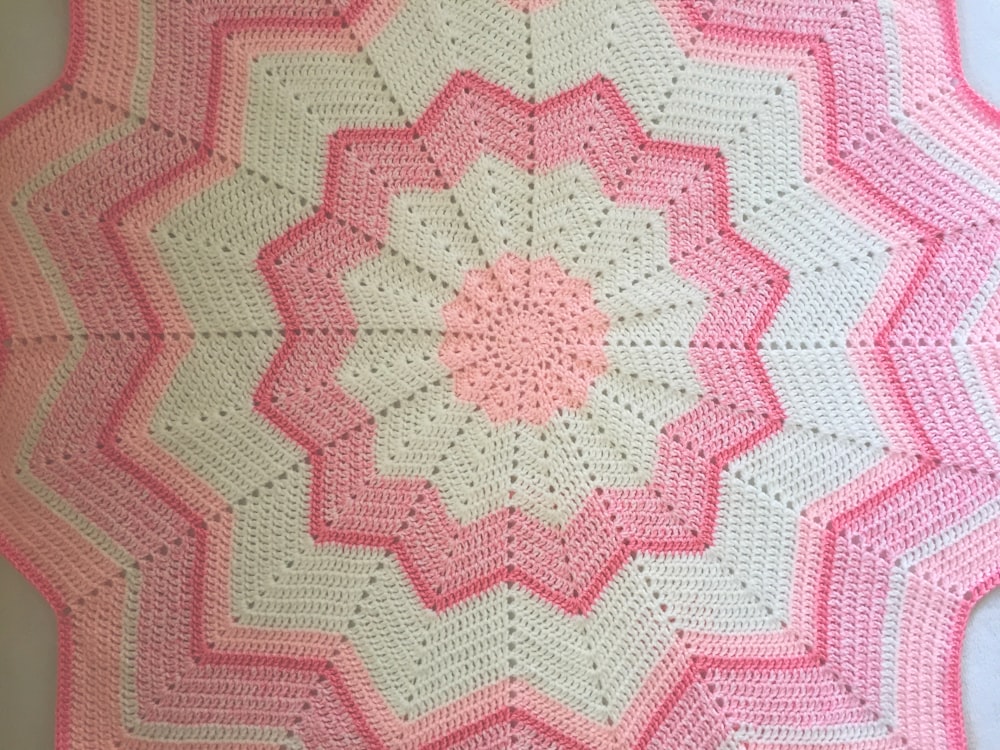 une couverture au crochet rose et blanc sur une table