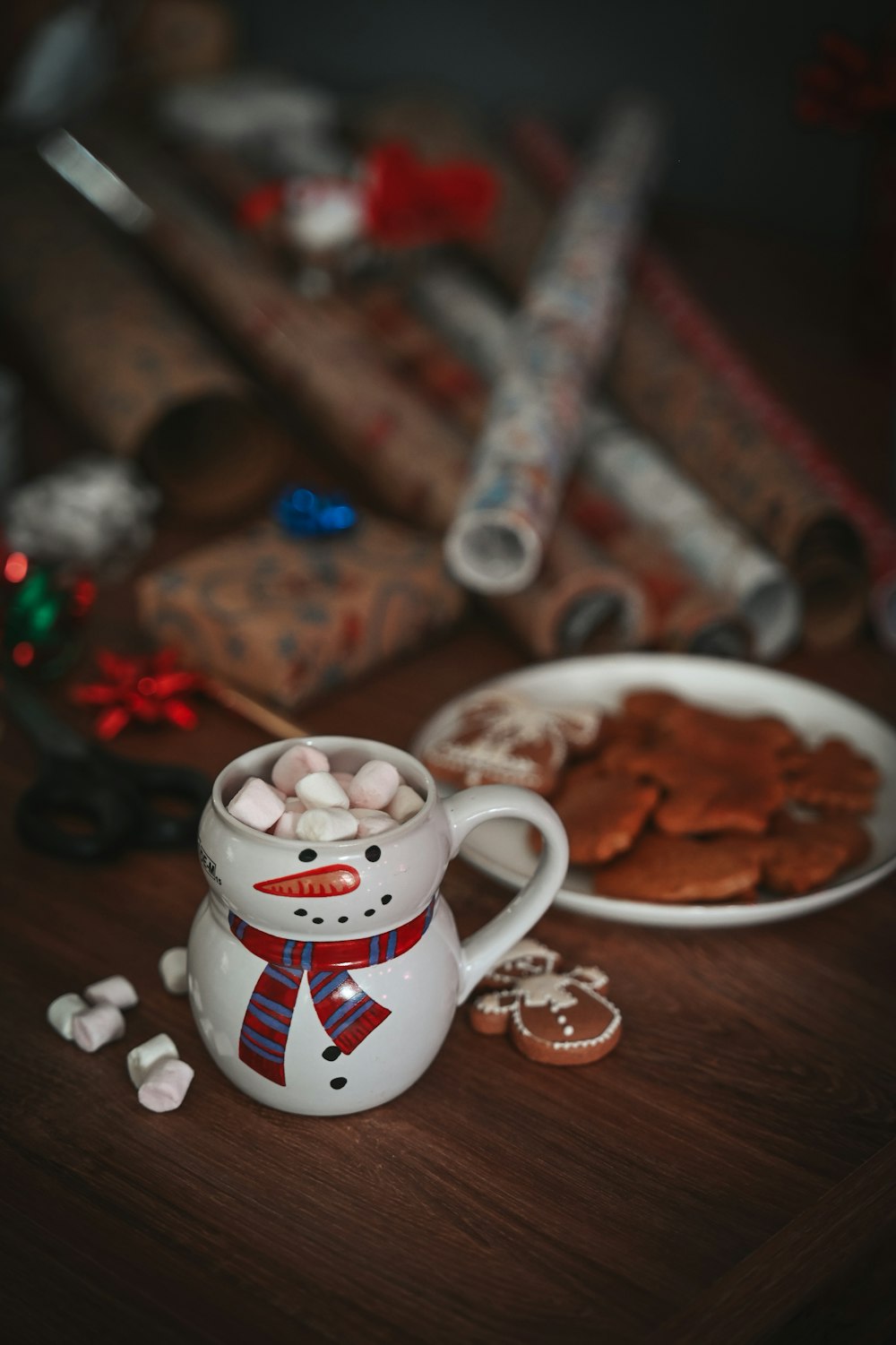 a mug with marshmallows in it next to a plate of cookies