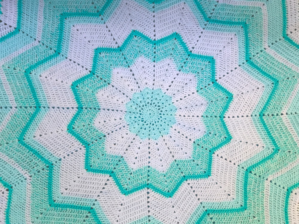 a blue and white crocheted blanket with a circular design