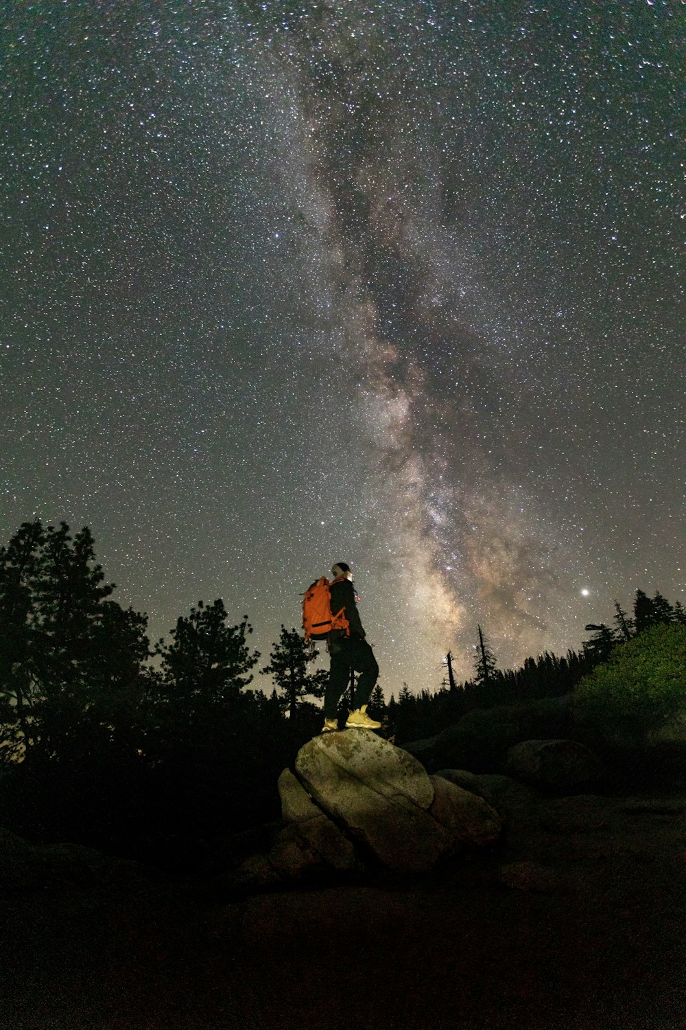 a man standing on top of a rock under a night sky filled with stars