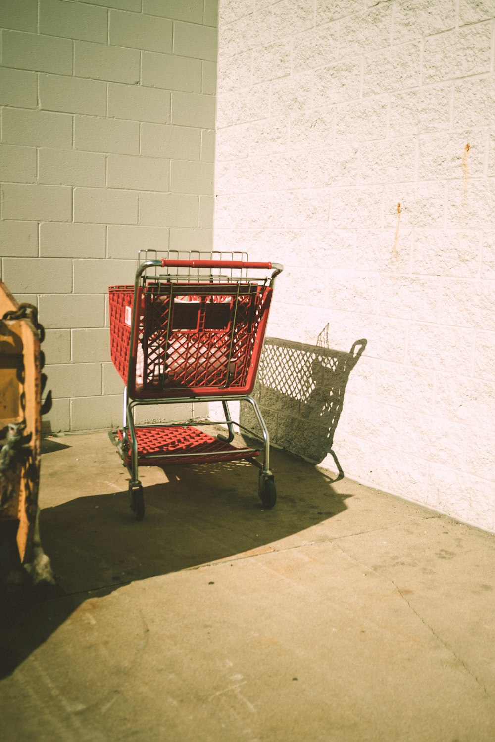 a red shopping cart sitting next to a white wall