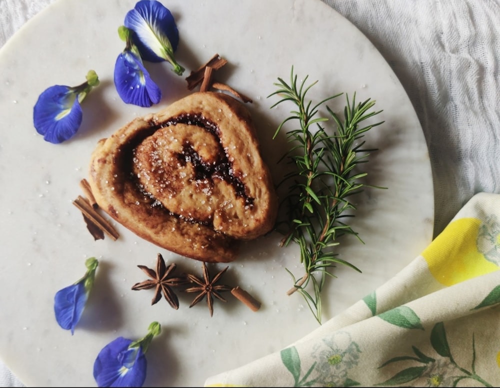 un rotolo di cannella su un piatto bianco con fiori blu