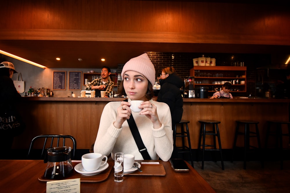 a woman sitting at a table with a cup of coffee