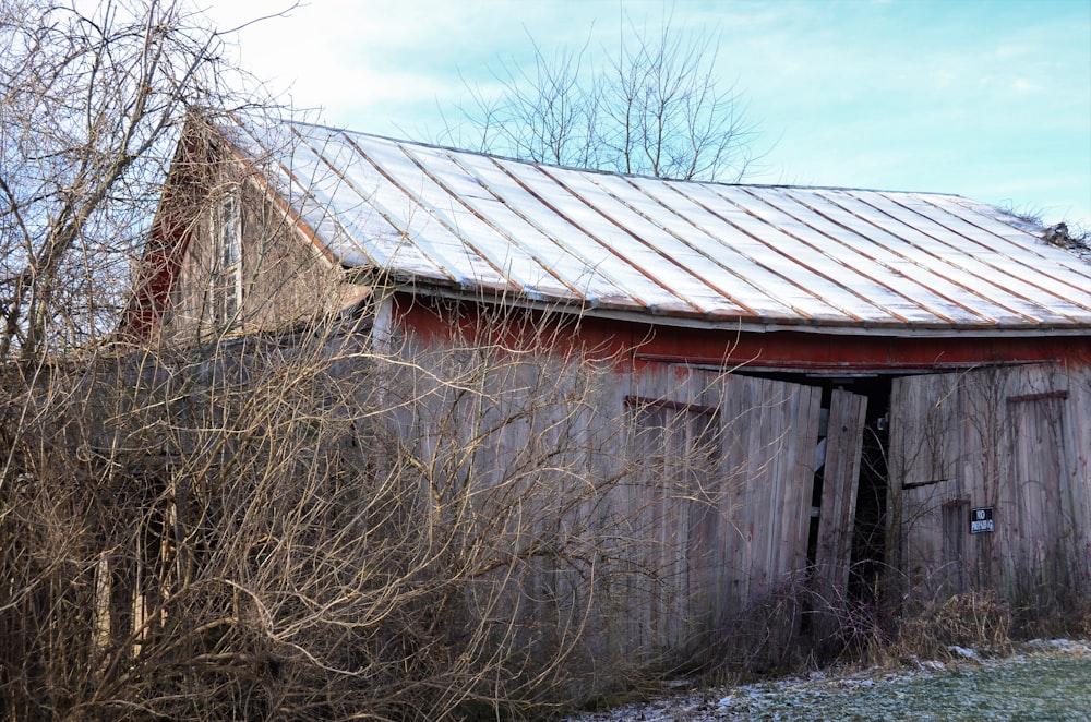 a red barn with a metal roof and snow on the ground