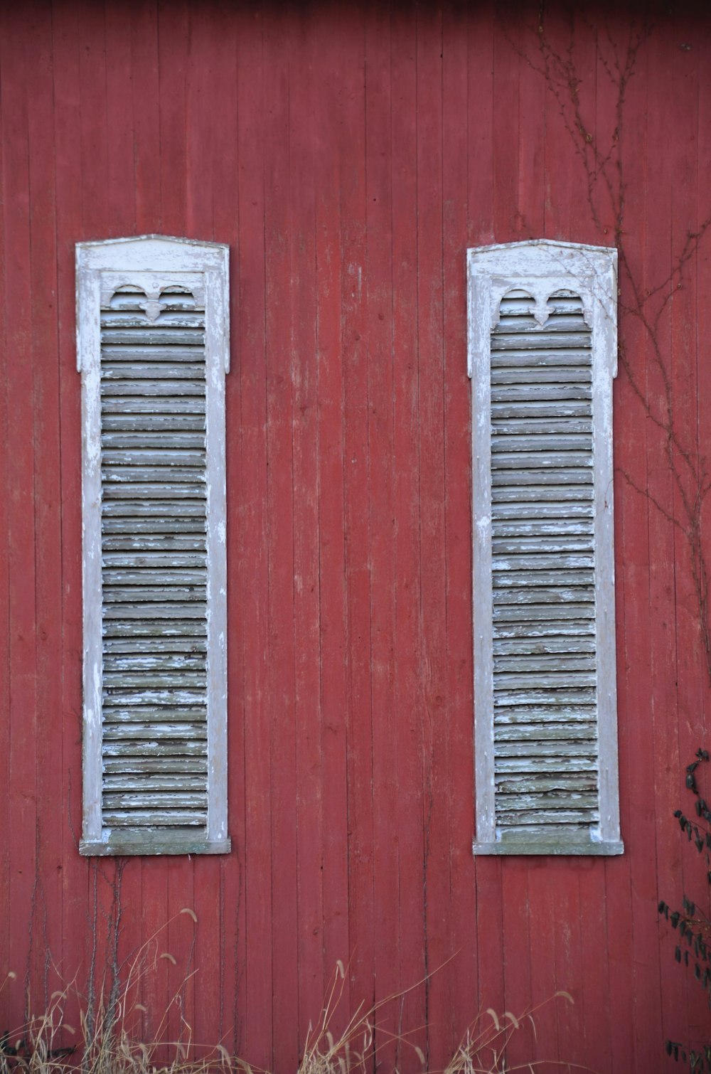 a red building with two windows with shutters