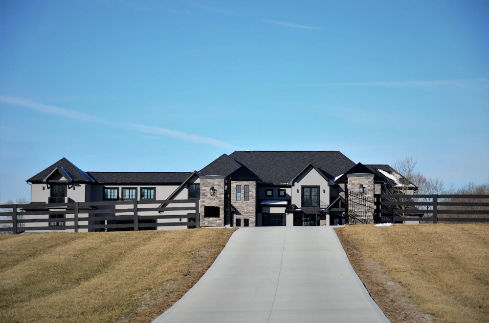 Long, clean concrete driveway leading up to a house under a blue sky