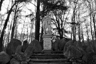 a statue sitting in the middle of a forest