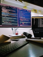 A calm workspace with dual monitors displaying secure coding practices and firewall settings.