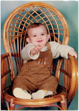 A cheerful baby sitting in a high chair with a colorful bowl securely held by the nidofirme clamp, smiling during mealtime.