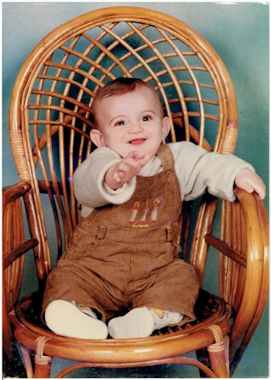 A cheerful baby sitting in a high chair with a colorful bowl securely held by the nidofirme clamp, smiling during mealtime.