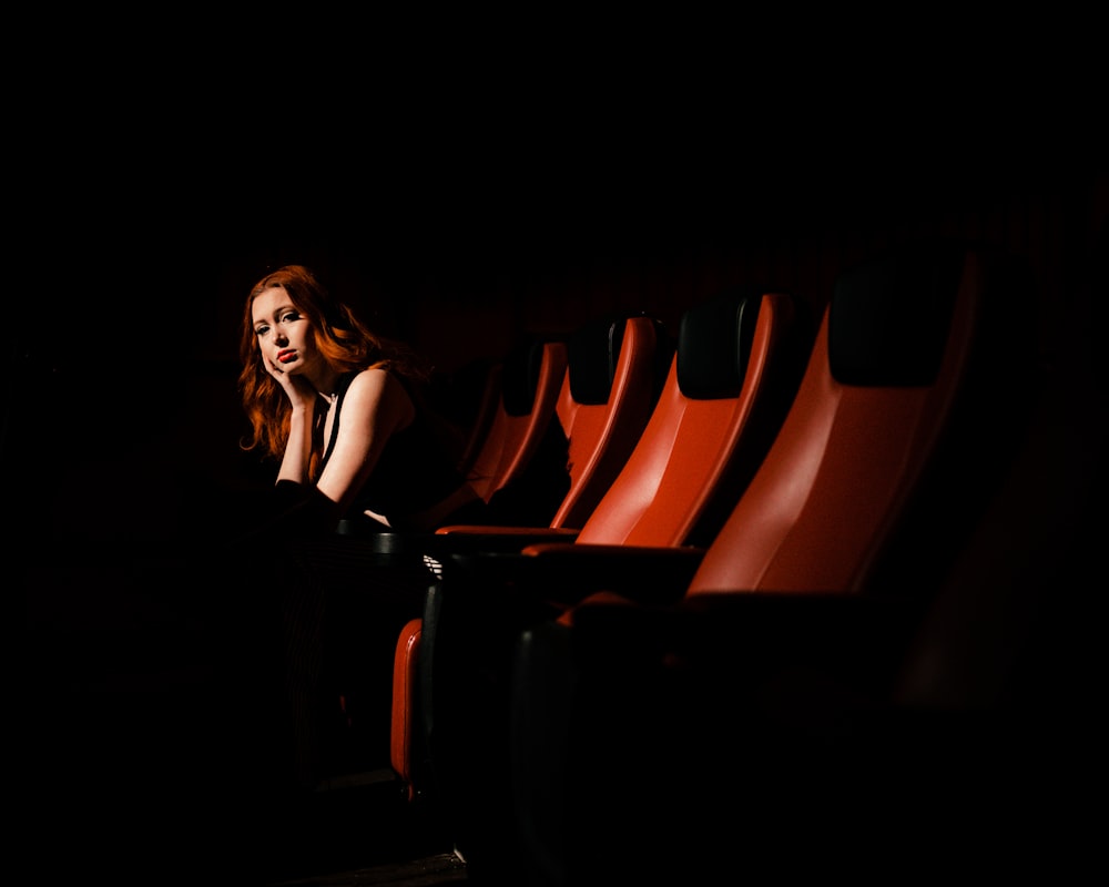 Una donna seduta in una fila di sedie rosse