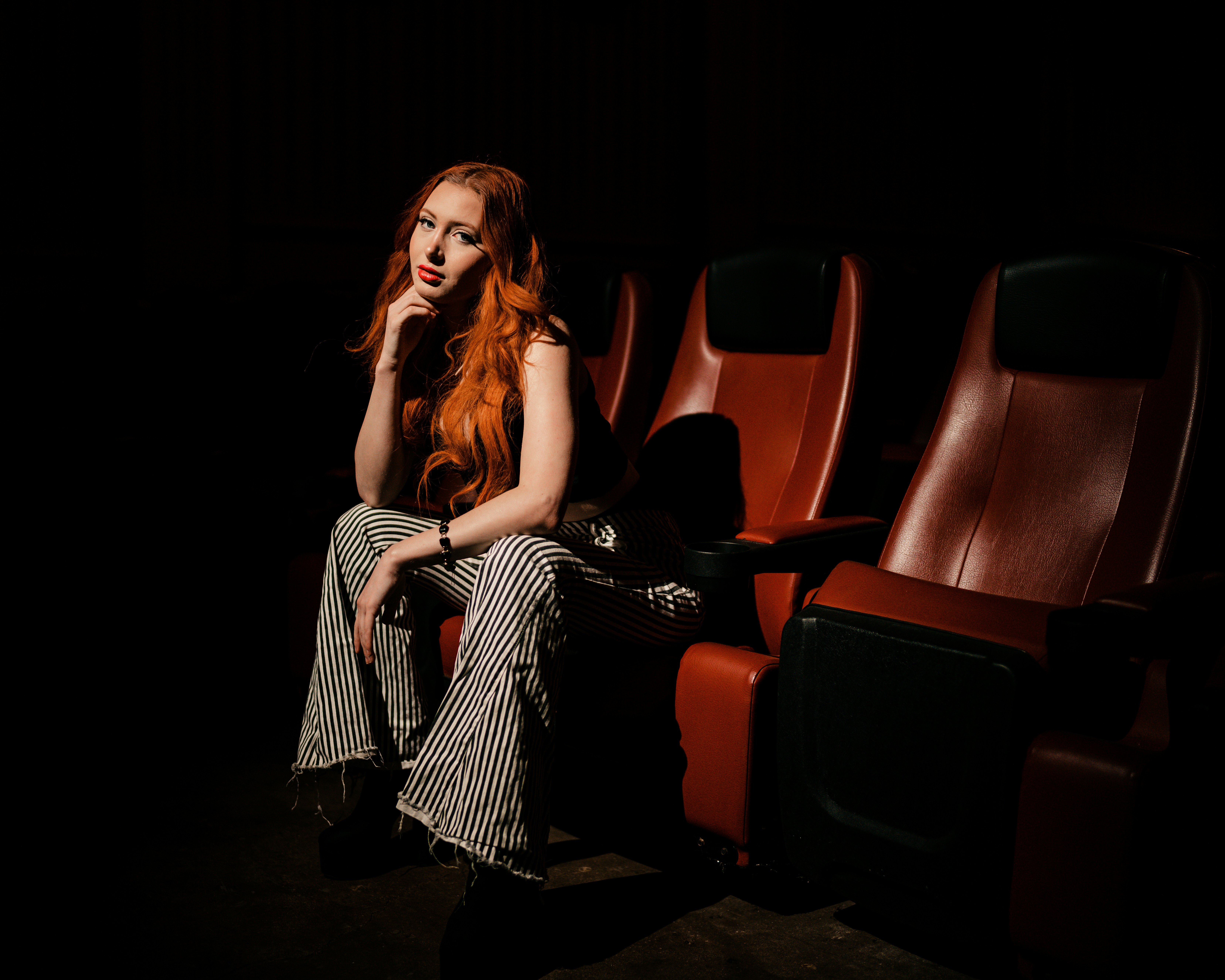 a woman with red hair sitting in a theater, 