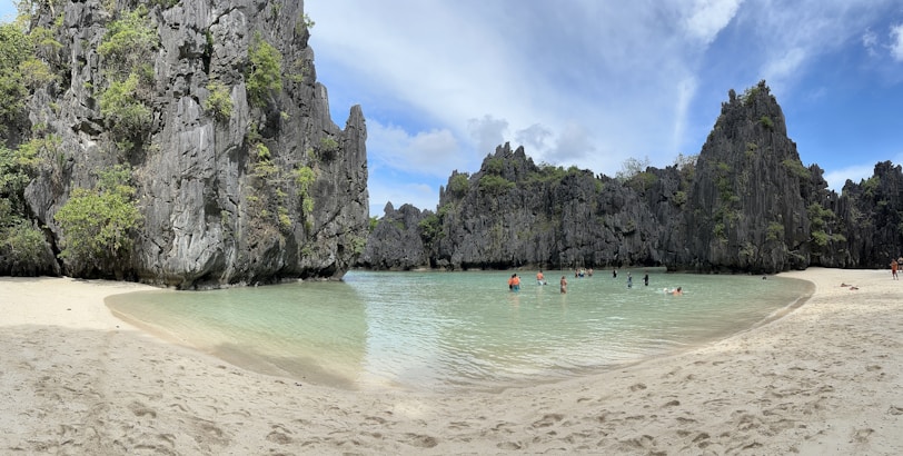 A group of tourists smiling on a beach with crystal-clear waters and limestone cliffs