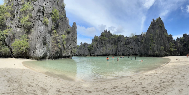 A hidden lagoon framed by limestone cliffs, water shimmering in shades of blue and yellow.