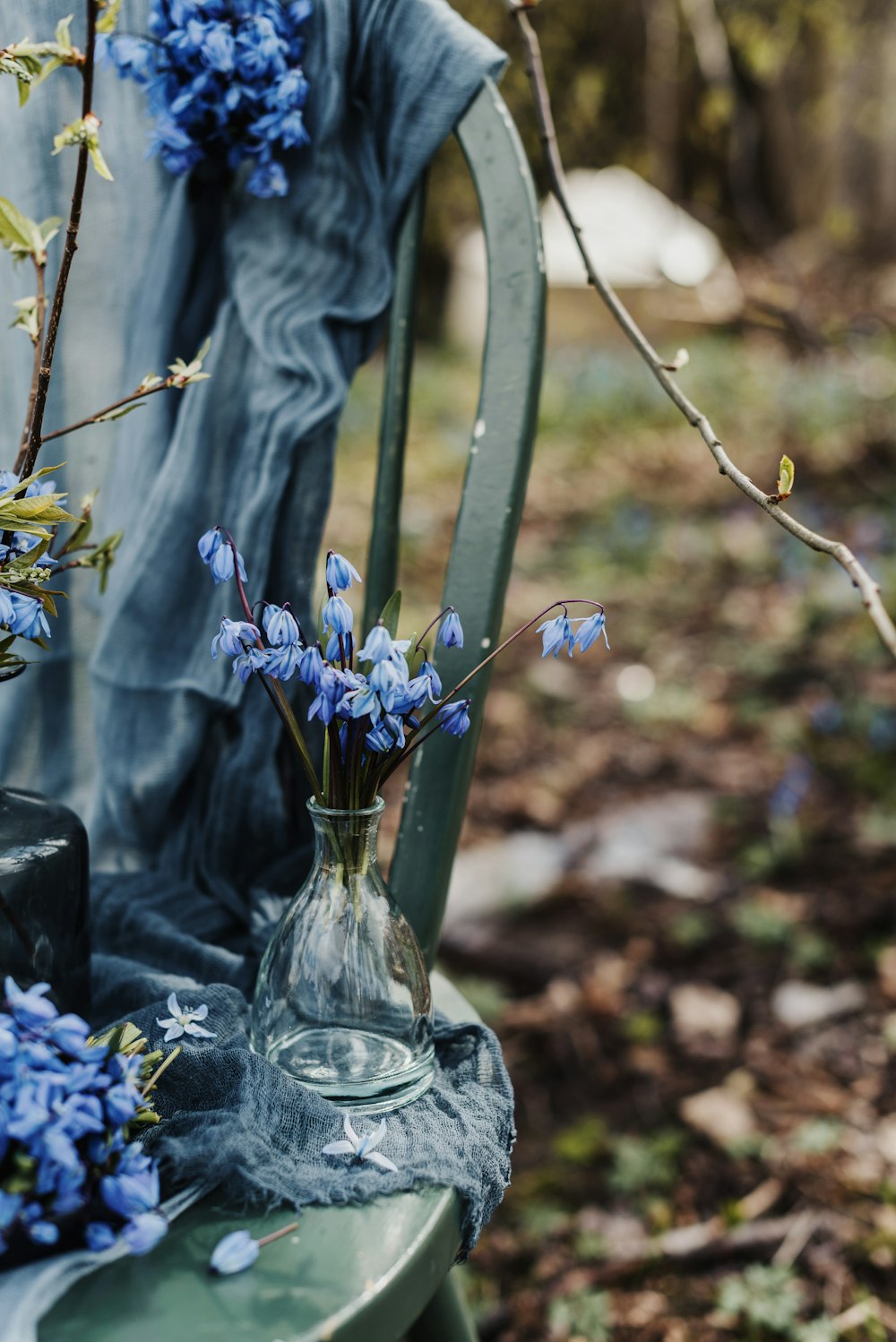 a vase of blue flowers sitting on a green bench