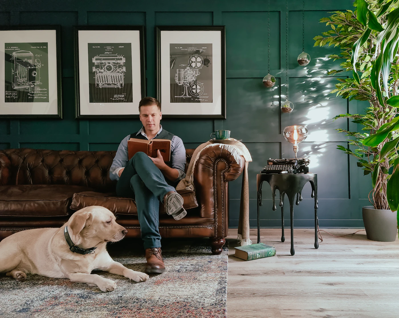 Man reading on a leather sofa with his dog resting nearby