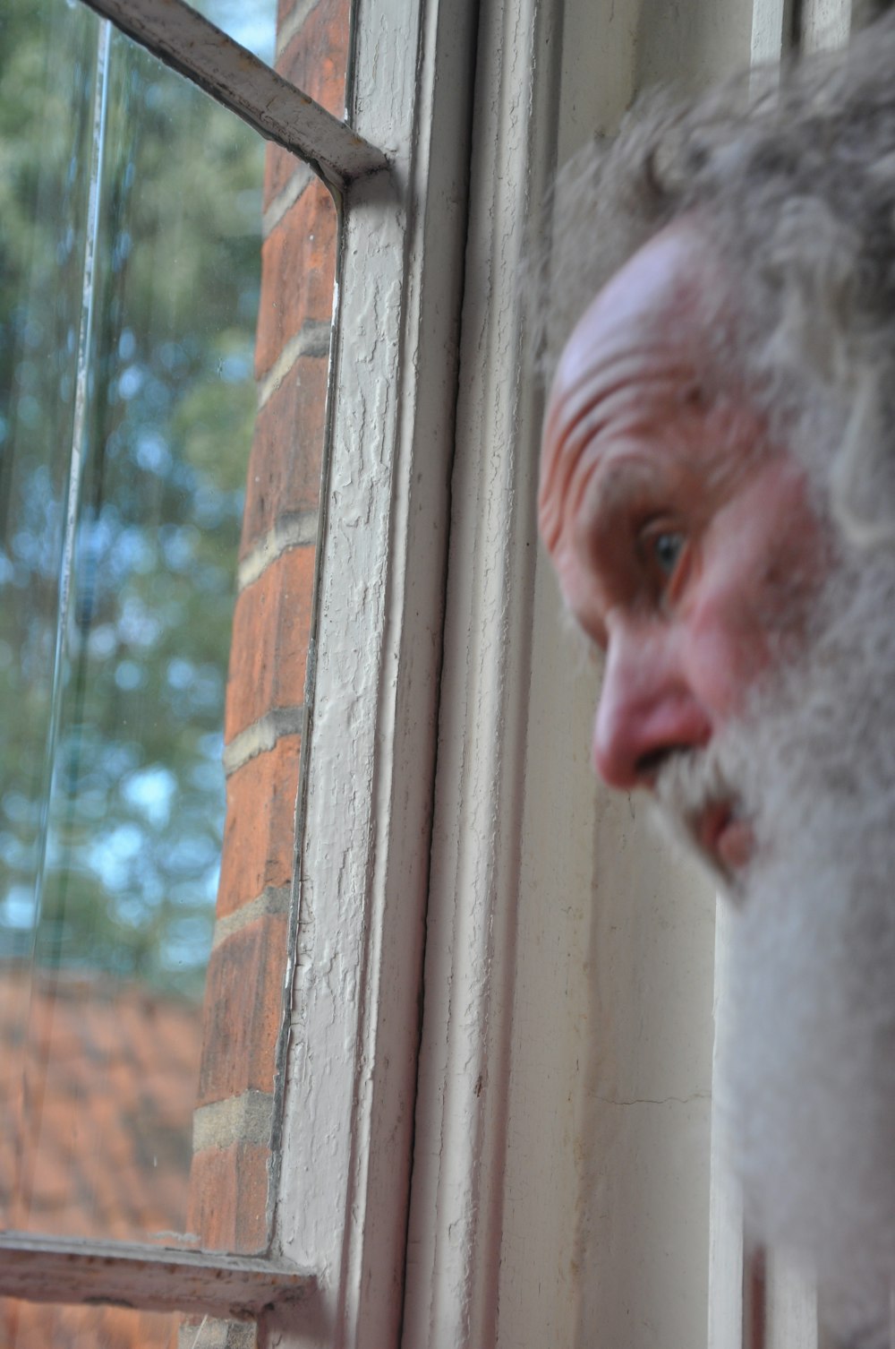 a man with a beard looking out a window