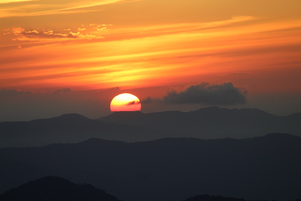 the sun is setting over a mountain range