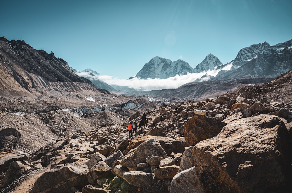 a man hiking up a rocky mountain with mountains in the background