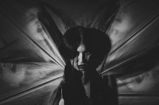 A shadowy silhouette of a confident femdomme against a black background, exuding power and mystery.