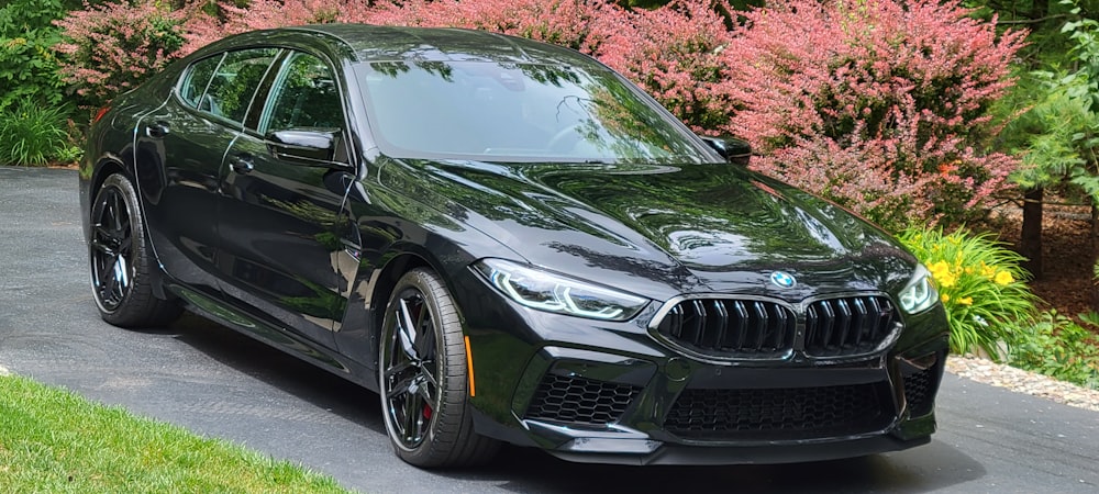 a black bmw is parked on the side of the road