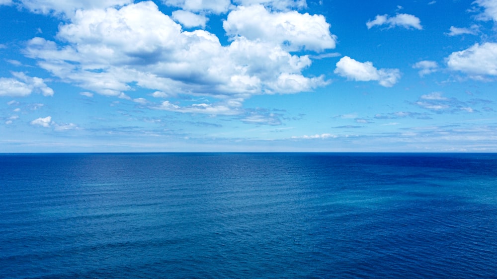 a large body of water under a cloudy blue sky