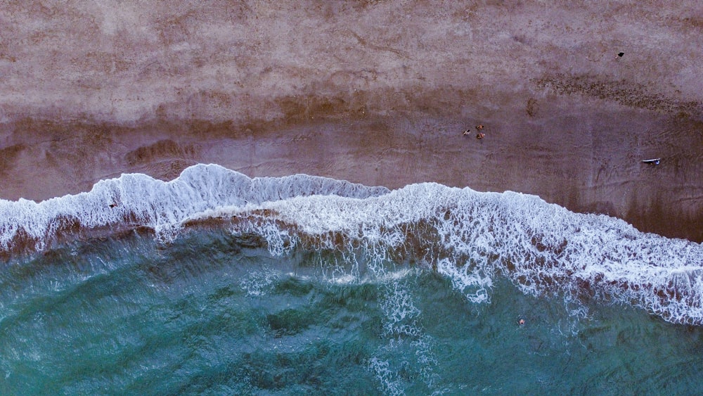 an aerial view of a beach with waves crashing on the shore