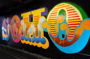 Close-up of a vibrant neon graffiti mural glowing against a dark wall.