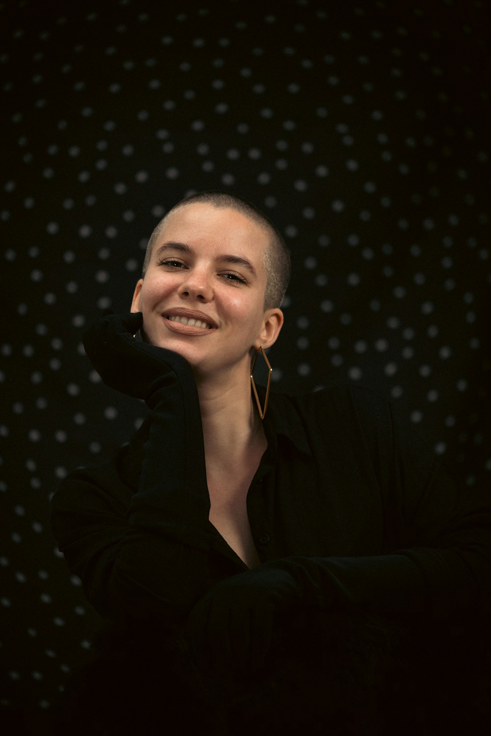 a woman with a shaved head smiles at the camera