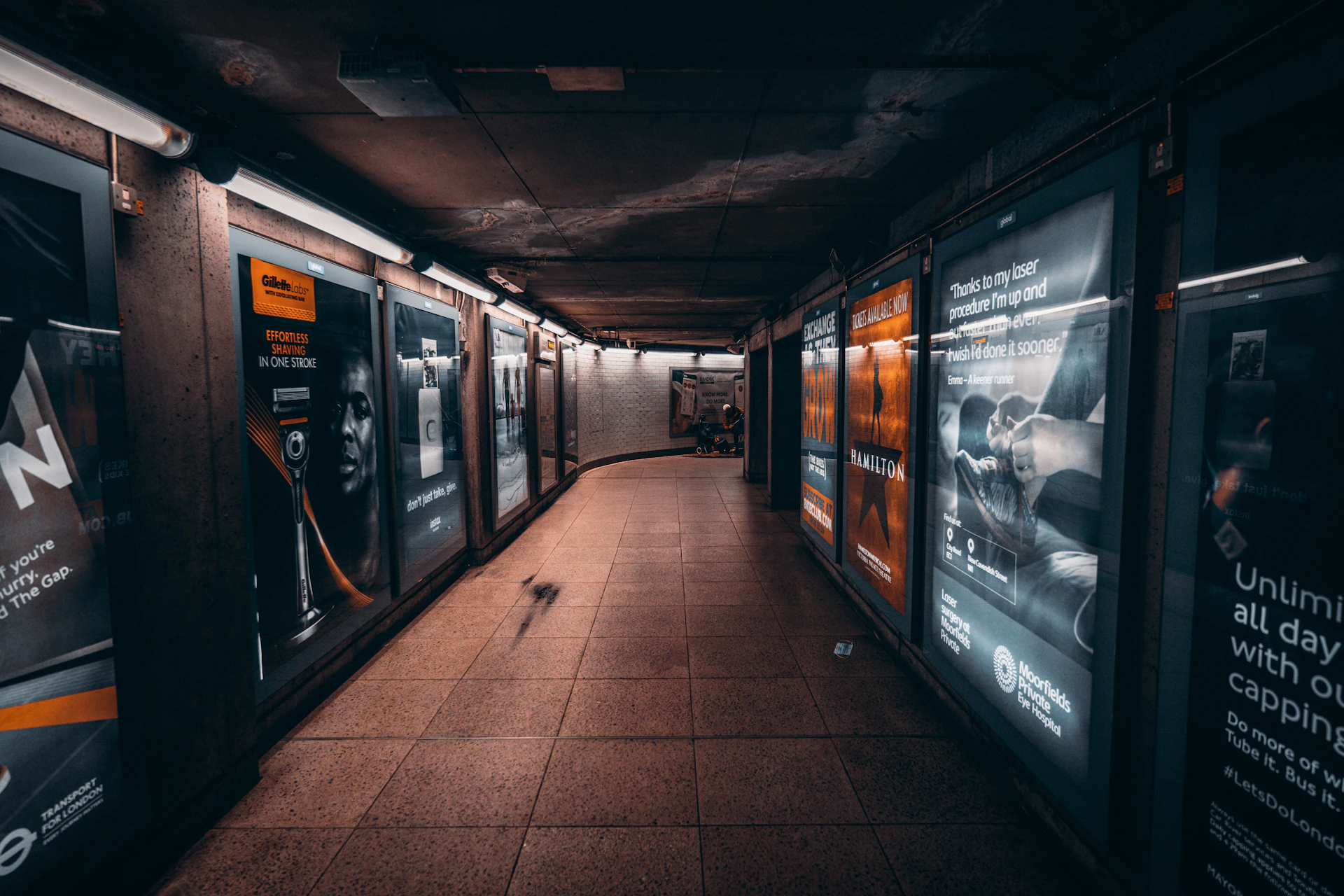 an empty subway station with posters on the walls